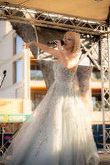 Elle Enchanted sings on stage in glittering ballgown