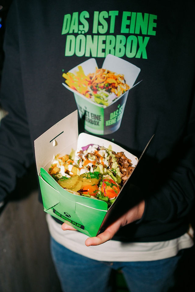 Close-up of a loaded dönerbox with beef, salad, fries, and garlic sauce, served at Kebap with Attitude's XBOX event.