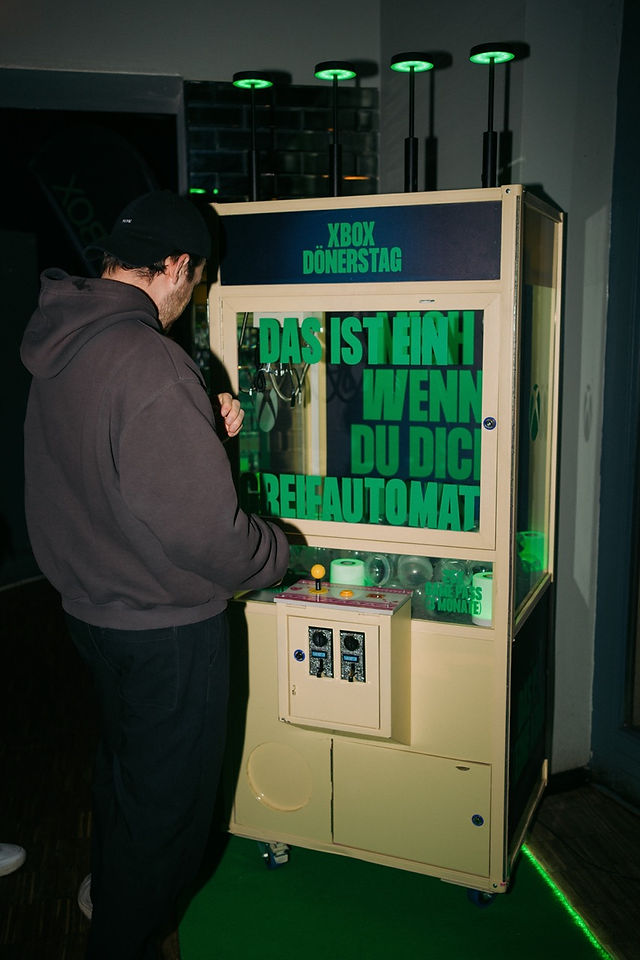 XBOX-themed claw machine "Spielautomat" with event attendee trying their luck at winning exclusive prizes