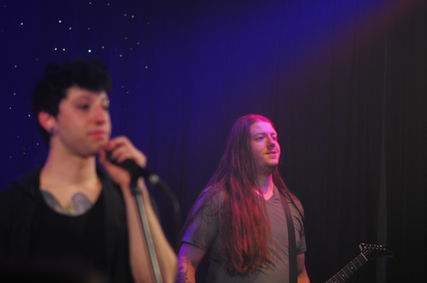 two men looking at the crowd from a stage
