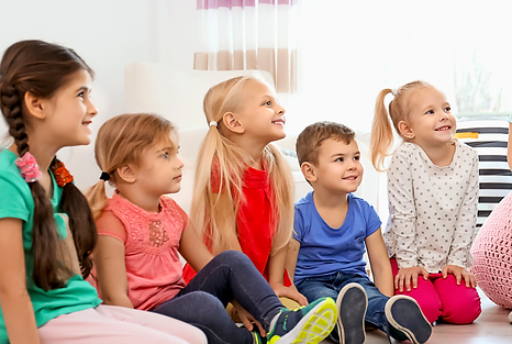 外国人の子供たちが笑顔の先生と明るい部屋で楽しく会話している