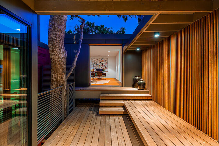 Outdoor wooden walkway with integrated lighting, wood-paneled walls, and a view into an illuminated interior room, Westridge Hillside Retreat.