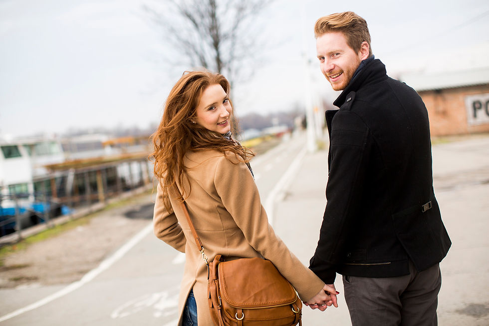 Couple walking and holding hands, looking back and smiling