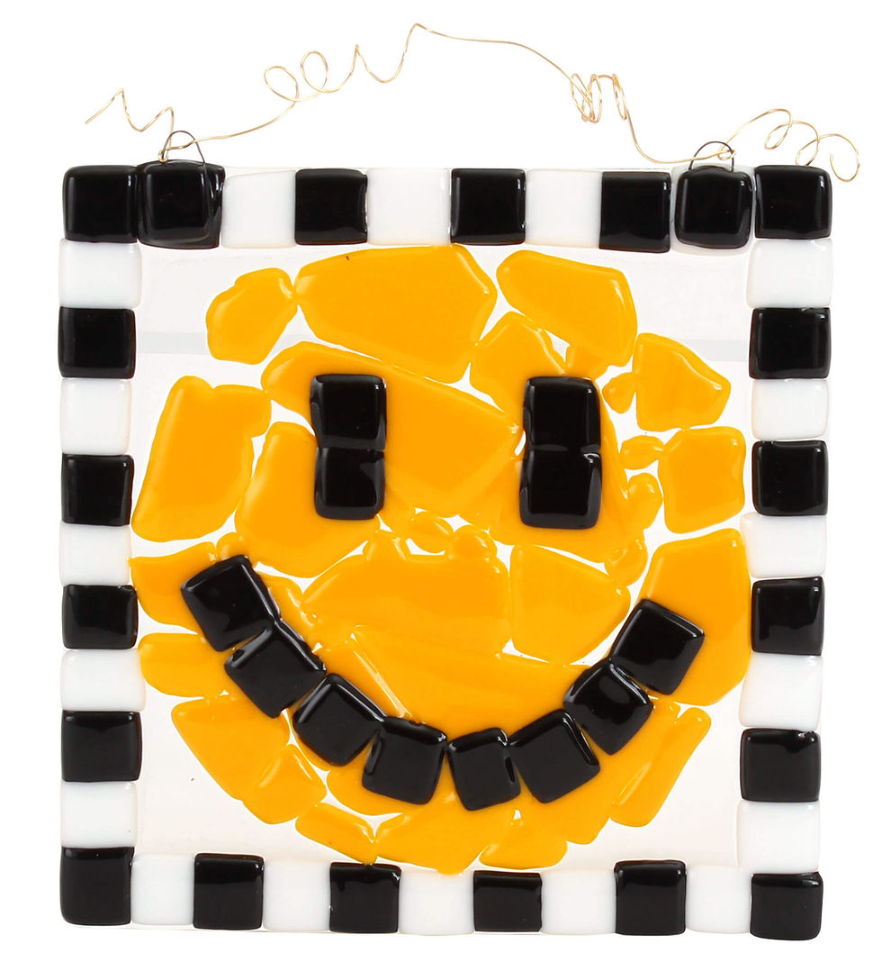 Completed glass fusing project featuring a smiley face design made with yellow and black glass pieces on a white background