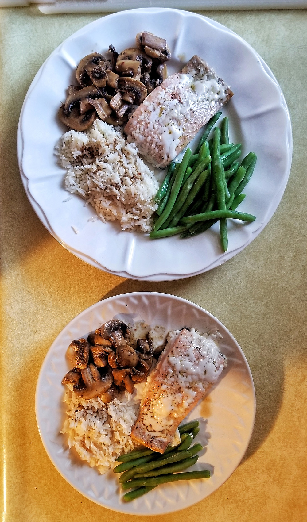Two plates featuring salmon, mushrooms, green beans, and rice.