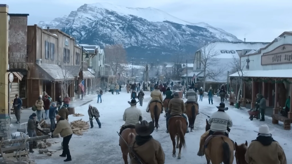 A snowy Jackson, full of people. Some riding horses and others cutting lumber.