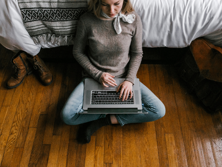 A woman types on a laptop seeking domestic violence victim services