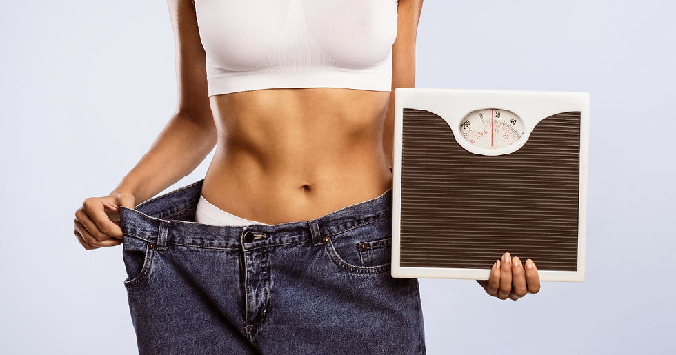 Woman showing weight loss progress by holding a scale and wearing loose jeans — visual success of realistic weight loss goals