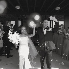 Newlyweds celebrate their exit, raising hands, showered with bubbles. Weddings.
