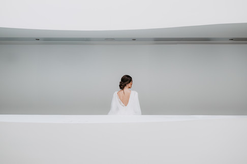 Novia posando de espaldas mostrando el peinado recogido y la espalda abierta del vestido antes de la