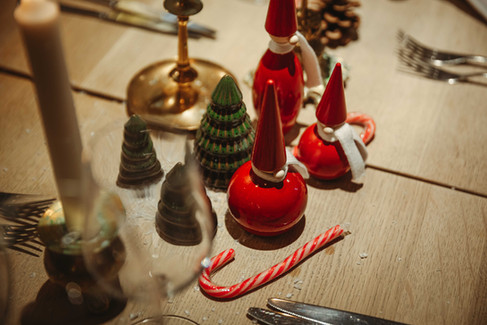 Närbild av juldekorationer på Fagerudd: små tomtar, minigranar, ljus och polkagriskäpp som skapar en varm och mysig julbordsstämning