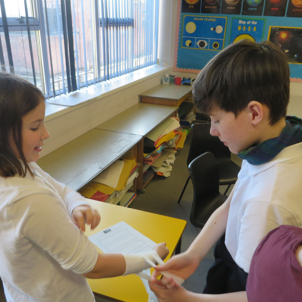 2 pupils practicing application of a wound bandage on each other.