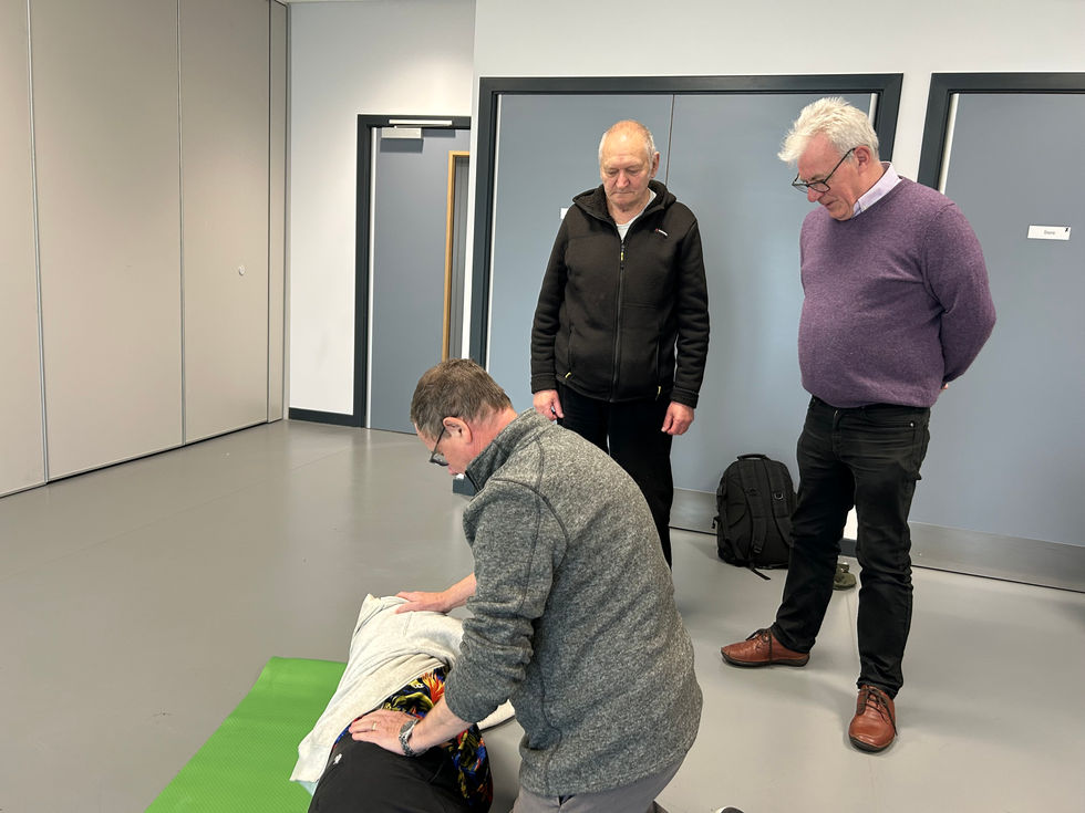 Members of Torry Men's shed practising stage 4 of recovery position