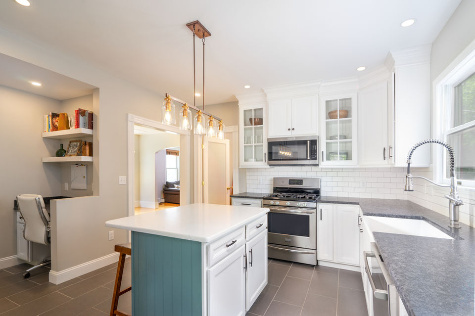Kitchen remodel with teal and white cabinetry, stone countertops, and pendant lighting