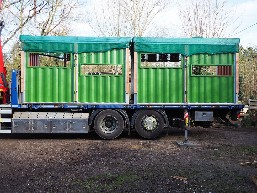 green roofed bird hides, with green coloured wall panels, sitting on a lorry.
