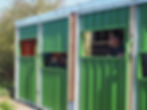 People peer out of a green coloured bird hide. The hide has a growing roof above.