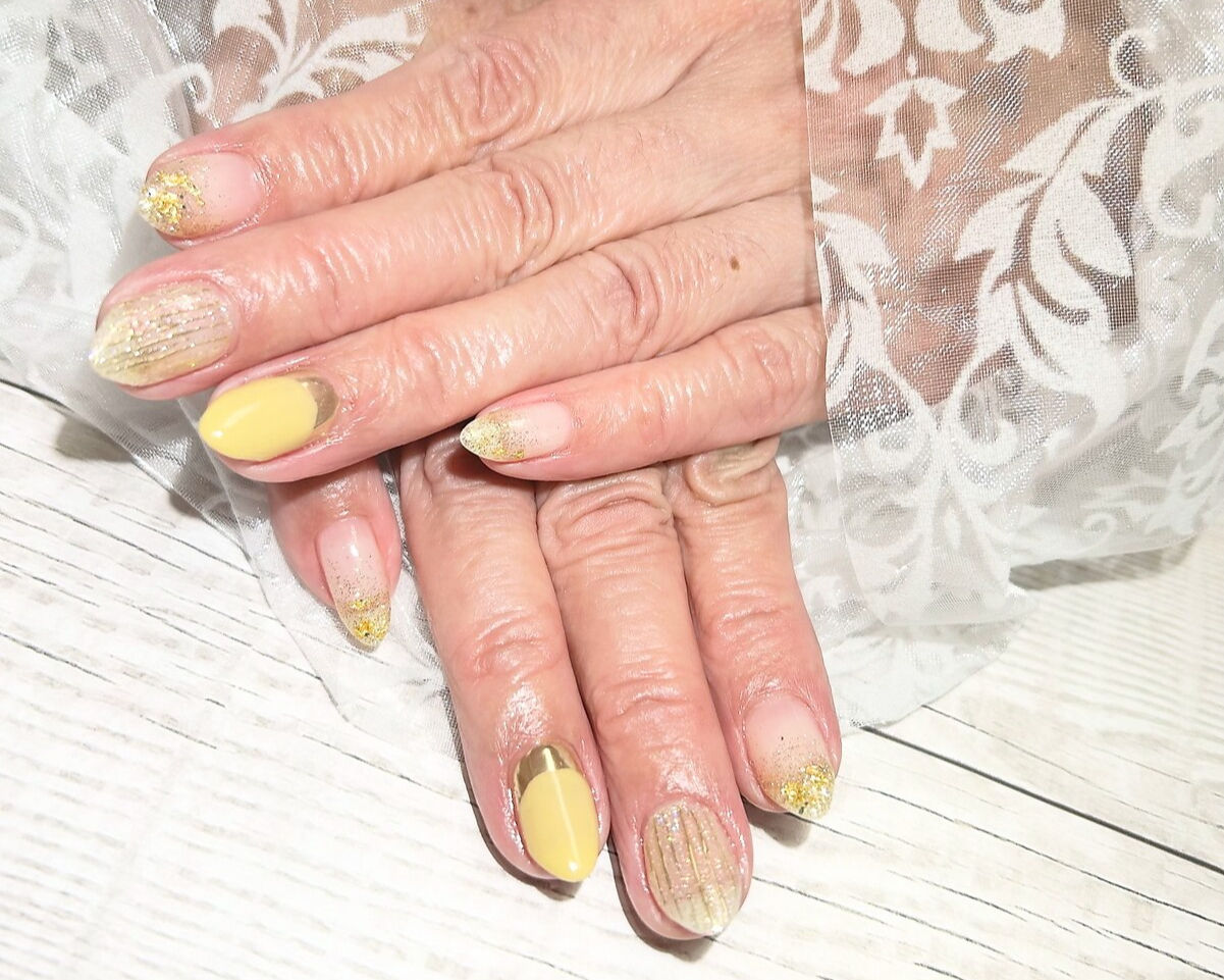 ケアカラーが施された、黄色とベージュの指先