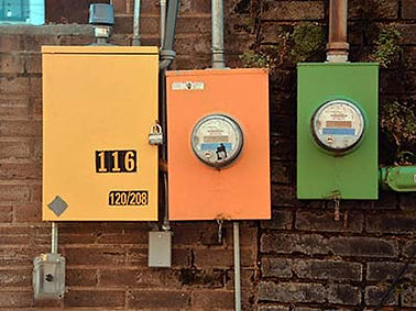 Electrical boxes on a brick wall in yellow, orange, and green