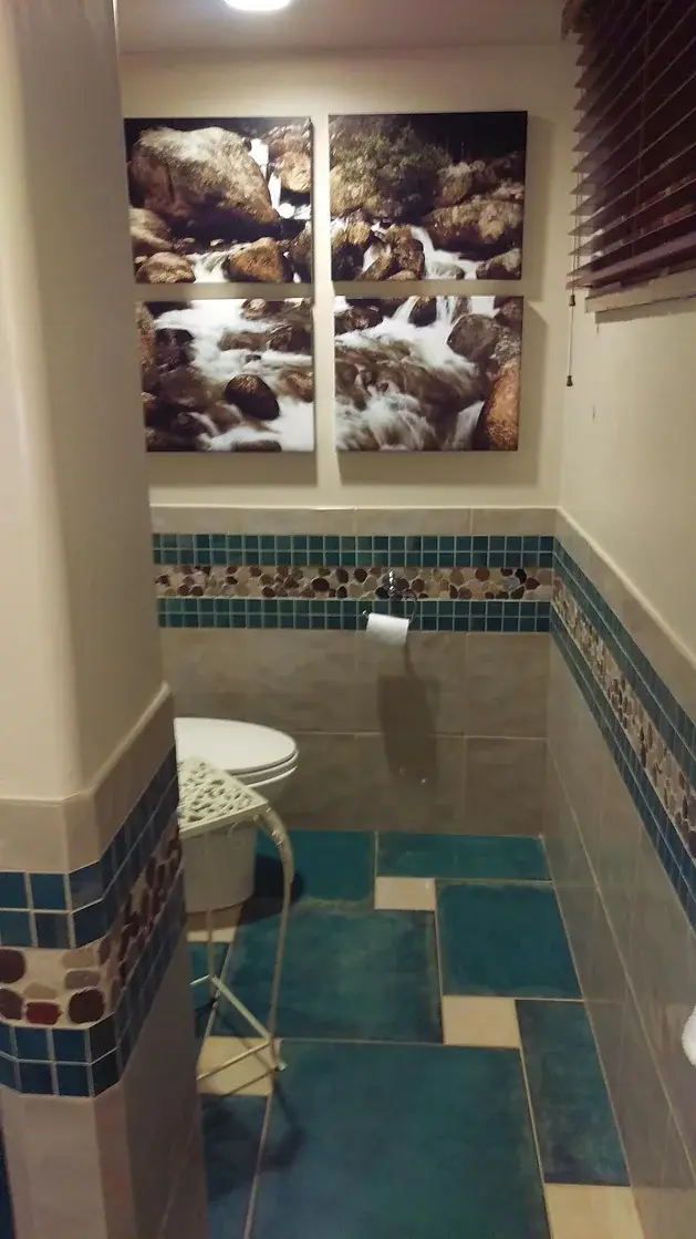 hotel bathroom with a toilet and two pictures on the wall tile boarder