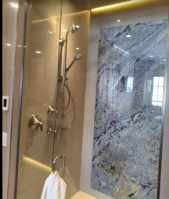 a shower with a blue granite wall behind it