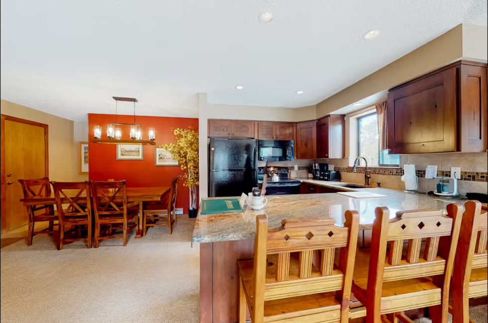 a kitchen with a dining table and chairs and a refrigerator