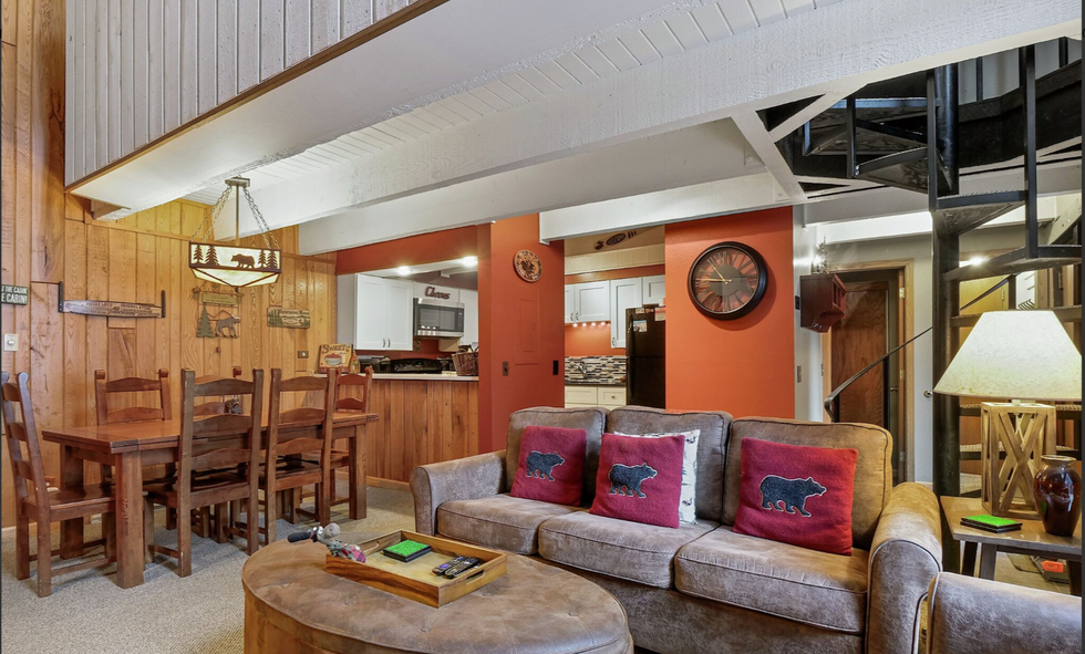 a living room with a brown couch and red pillows with bears on them
