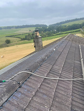 Dark tiled roof with chimney and beautiful countryside background
