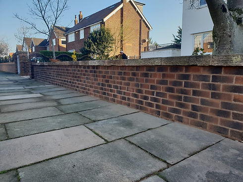 Suburban street scene with a brick house and bare trees under a clear blue sky