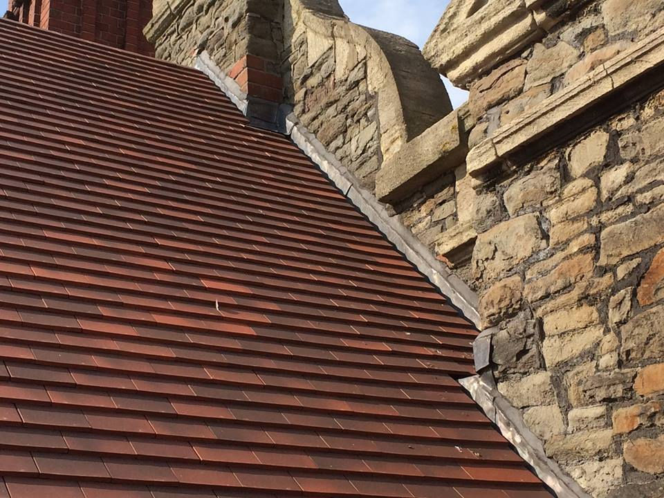 Red tiled roof next to stone building