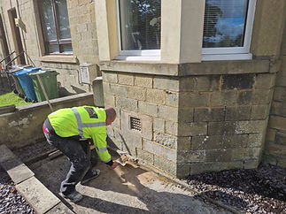 Construction worker inspects damaged brickwork on a building's exterior