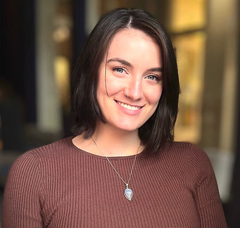 Head shot of Megan with a blurred background, Brown Sweater and Necklace