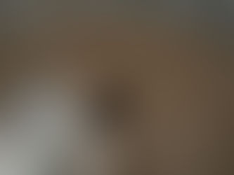 Man in beige coat relaxes on boat, hands behind head, with closed eyes. Calm water in the background; a sense of tranquility pervades.