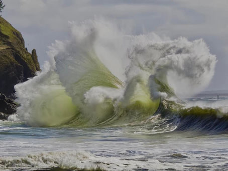 A wave crashes on a rocky headland sending spray and foam into the air in shapes that can be interpreted differently by the observer.