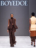 Models walk runway in brown and beige outfits with fringe accents. "BOYEDOE" logo in background. Elegant and confident mood.