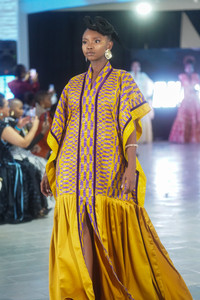 Model in vibrant checkered black and yellow dress on runway