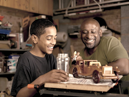 A father and son working on a project together and smiling.