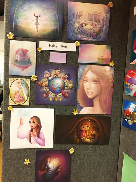 A display of artwork on a gray wall. The artwork has golden flowers decorating it.