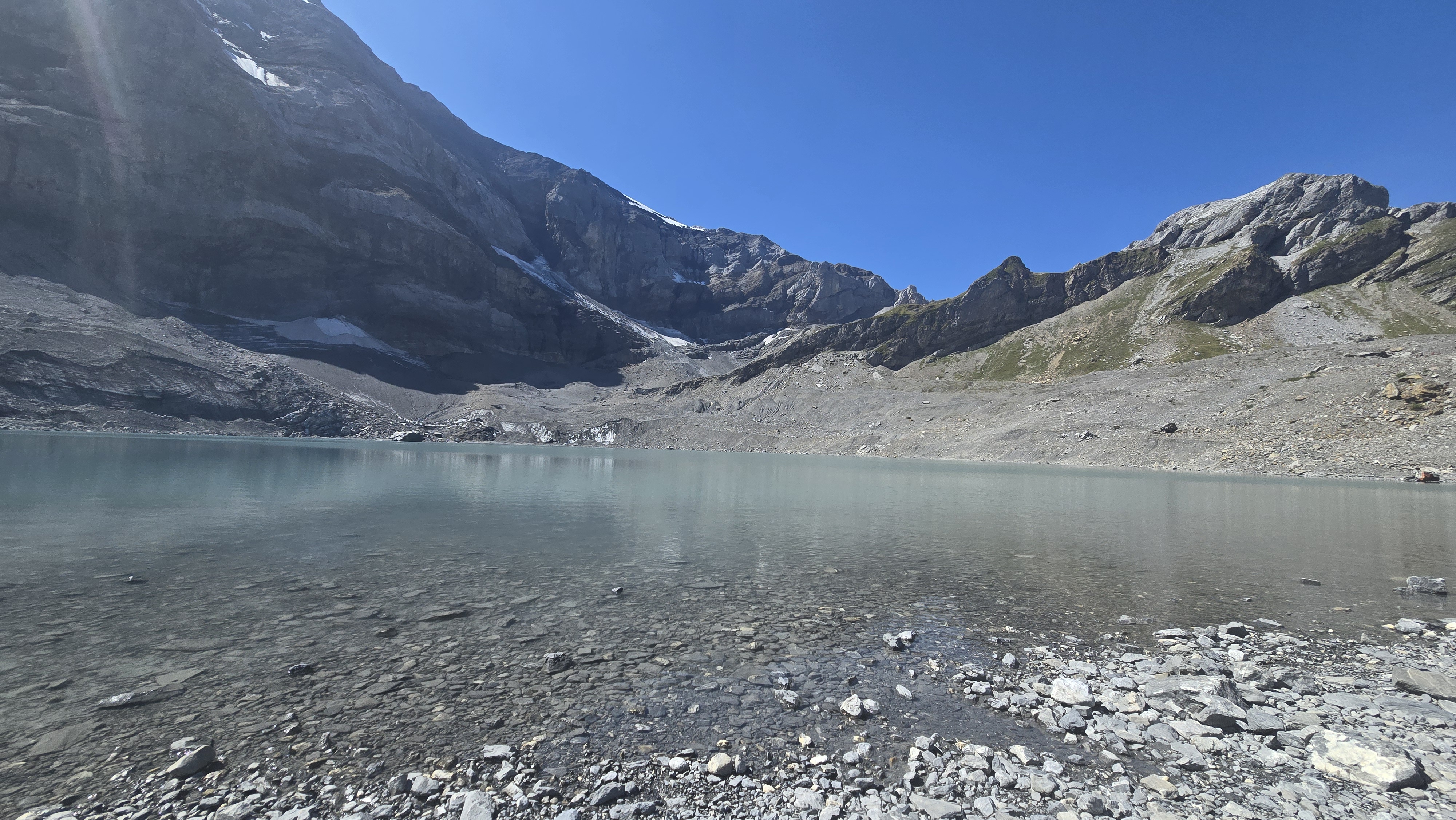A stunning panoramic view from the Clariden mountain trail overlooking a serene alpine lake.