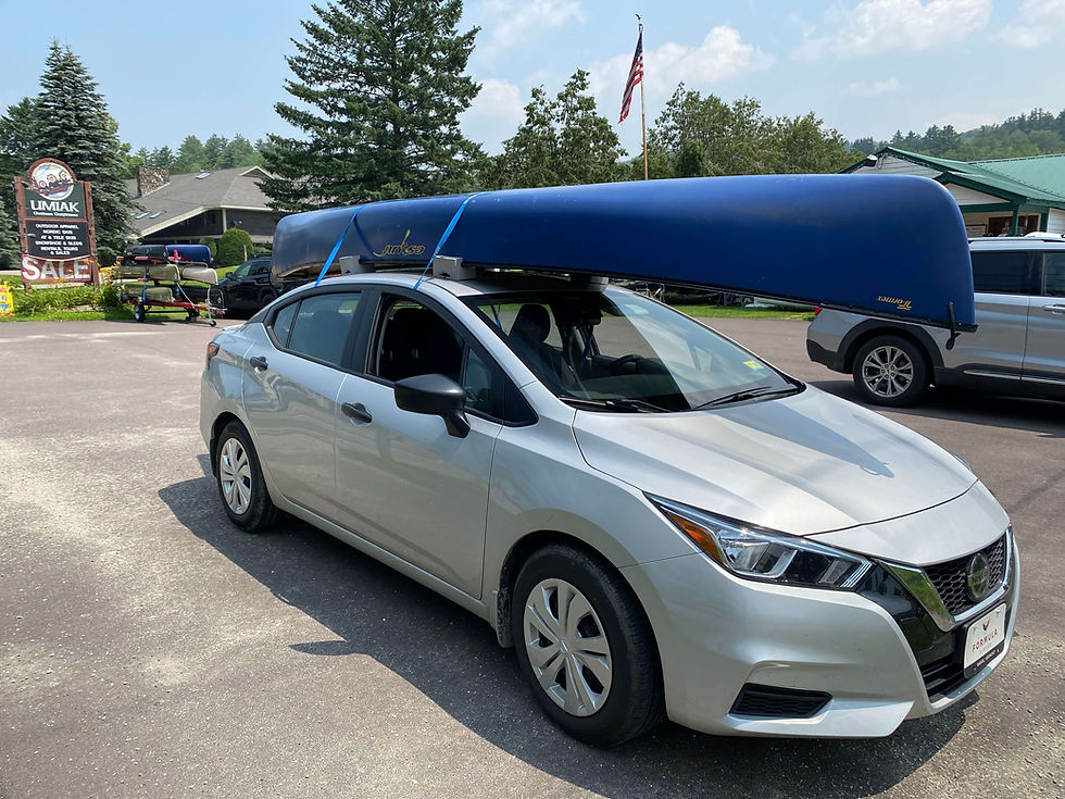 A canoe is secured to a silver car without a roof rack parked at Umiak in Stowe, Vermont.
