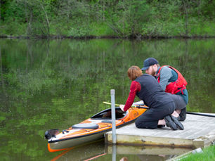 A man prepares to test a paddle kayak on Umiak's pond with assistance from a staff member.