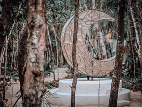 A serene crescent moon sculpture nestled among the lush greenery at Lunita Jungle Retreat Center in Mexico.