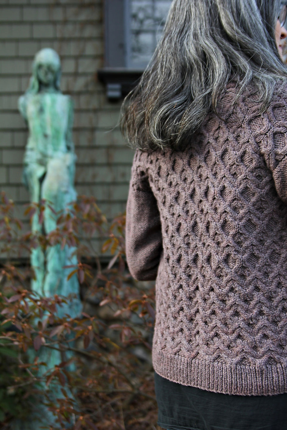 woman stands with her back to camera in knit sweater