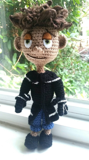 A doll wearing a black coat and jeans meant to look like Wybie - a character from the movie Coraline