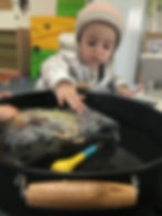 Toddler examining an ice block with dinosaurs in them