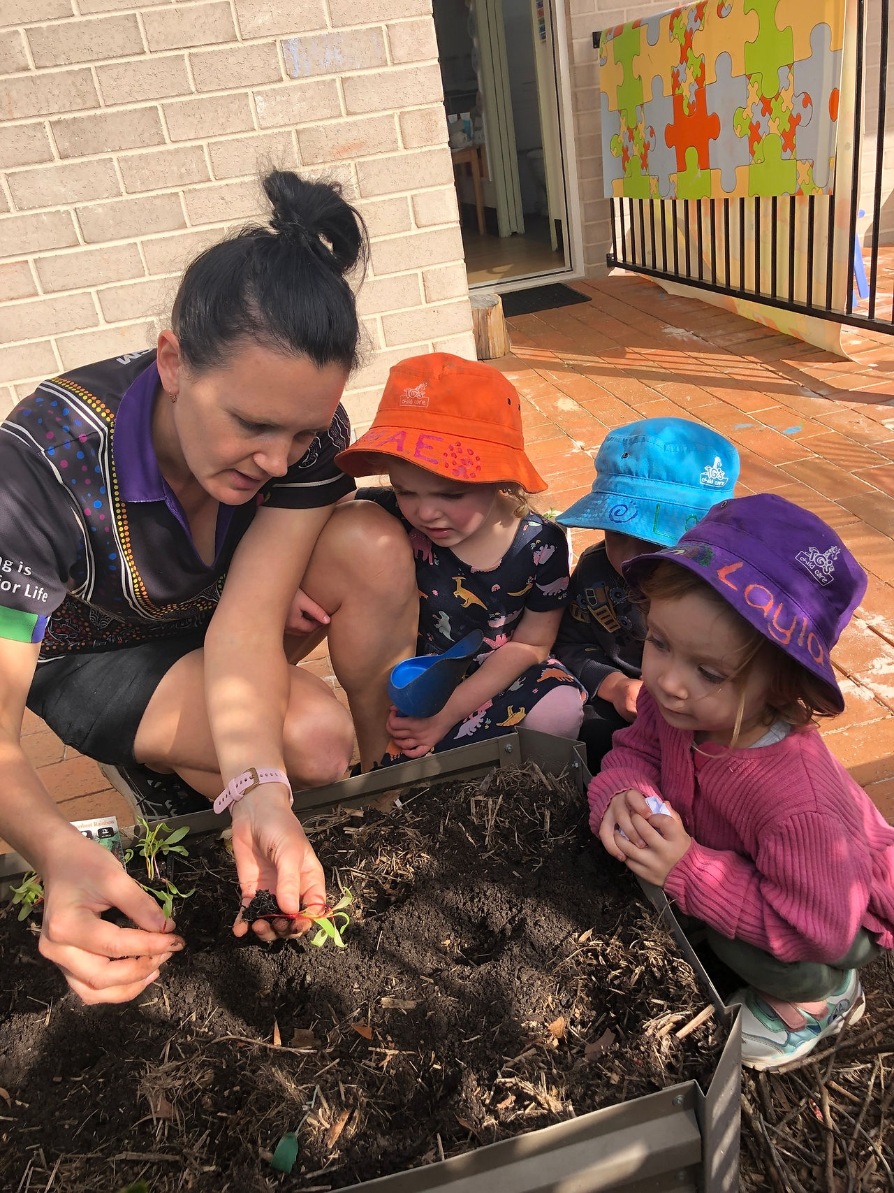 TG's High St Educator with children gardening | TG's Child Care