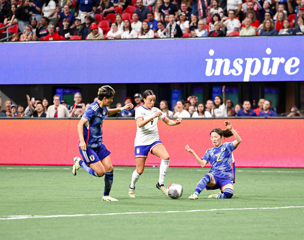 Women’s soccer action: Japan and US players battle for the ball in a packed stadium, with inspire on the LED board.