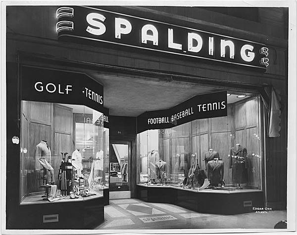Black-and-white Spalding sports store window display with mannequins and gear for golf, tennis, football, and baseball.