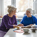 Two elderly women sitting at a kitchen table in an assisted living community.jpeg
