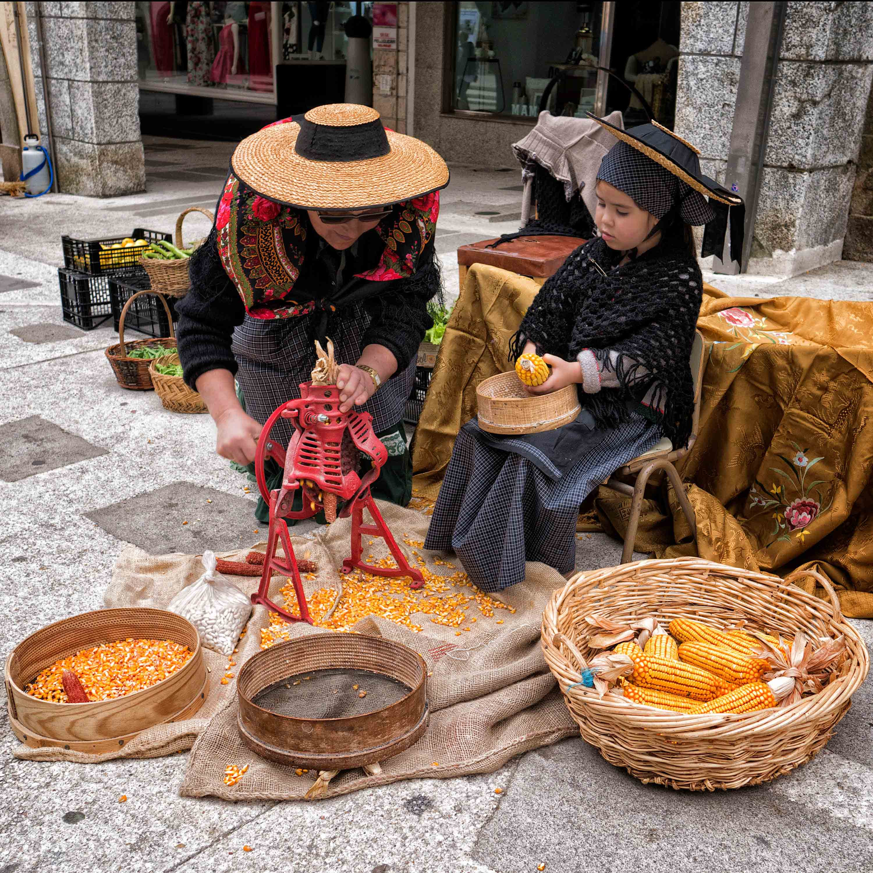Abuela y nieta desgranando manualmente el maíz con sus trajes típicos... 