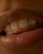 Thick lips with white teeth and wet tongue slightly visible as part of a sexological bodywork session